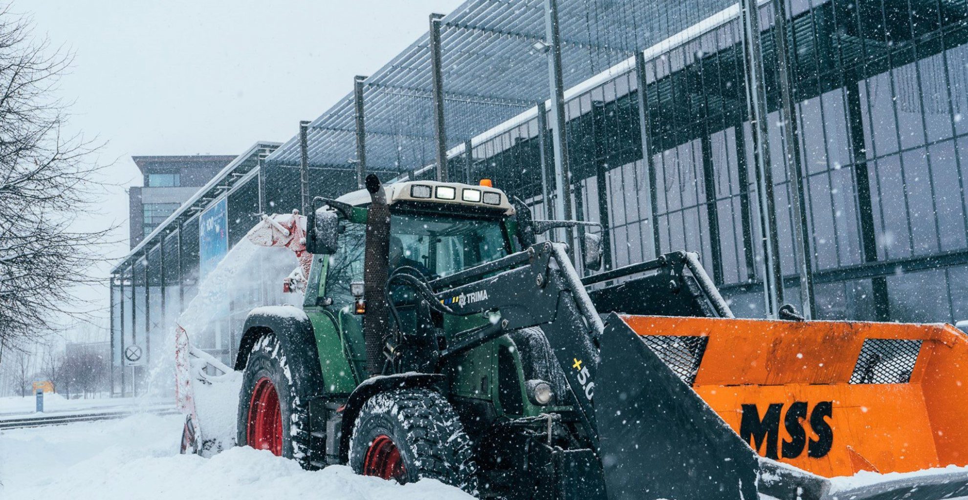 Bilde viser traktor med skuffe som måker snø